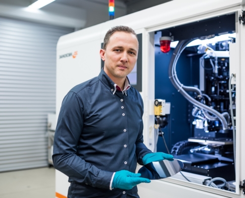 Ein Mitarbeiter der Technologieentwicklung steht neben der offenen Tür einer Laseranlage zur Waferbearbeitung.