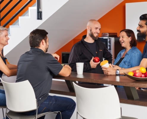 Mitarbeiter stehen lachend in der Küche von 3D-Micromac in Chemnitz und genießen die kollegiale, wertschätzende Atmosphäre des Arbeitgebers.